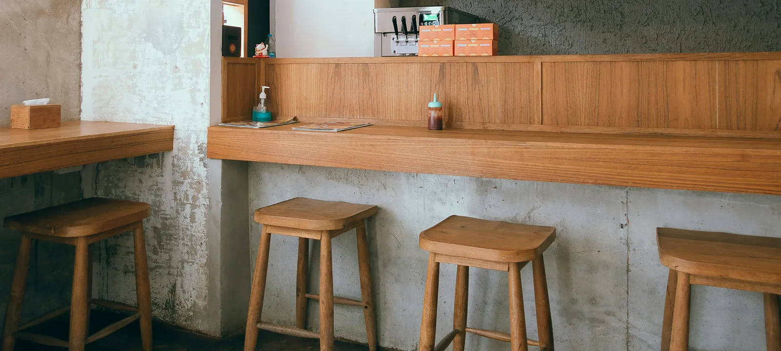 木のカウンターと丸い木の椅子が並ぶ、飲食店の店内